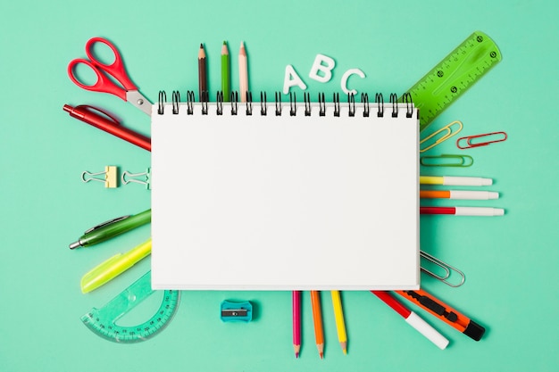 Cuaderno en blanco rodeado de útiles escolares de papelería.