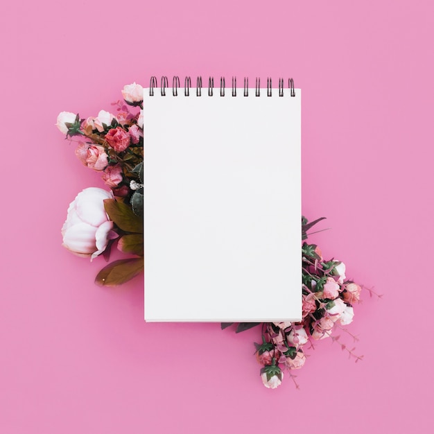 Cuaderno de bodas con hermosas flores sobre fondo rosa