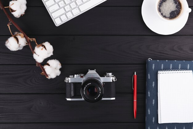 Cuaderno con camara y cafe en mesa.