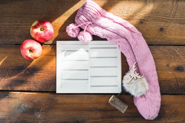 Cuaderno cerca de calcetines de punto y manzanas