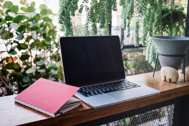 Cuaderno cerca de la computadora portátil en el jardín