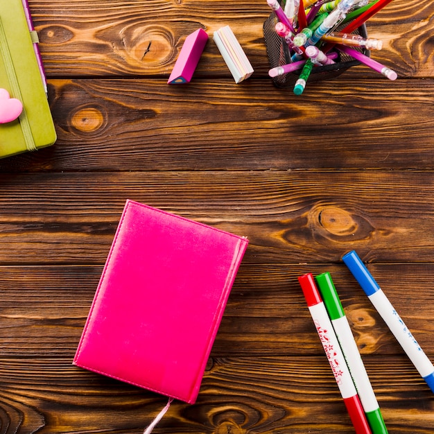 Foto gratuita cuaderno cerca de marcadores y gomas