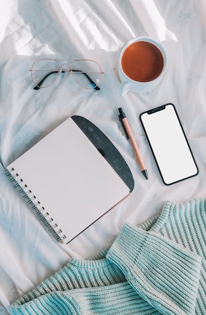 Foto gratuita cuaderno cerca de taza y teléfono inteligente