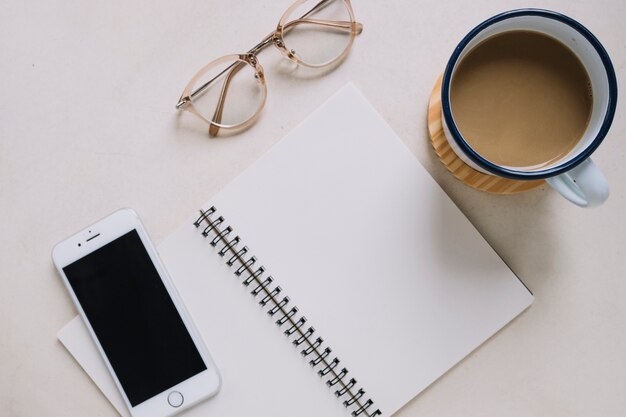 Cuaderno cerca de teléfono inteligente y café