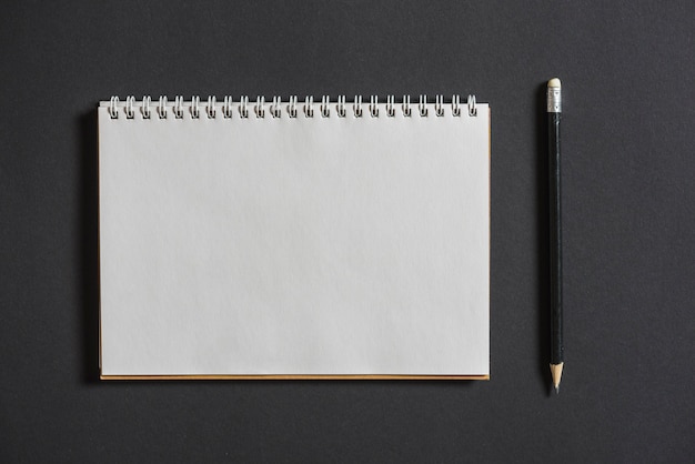 Cuaderno espiral con lápiz sobre fondo gris