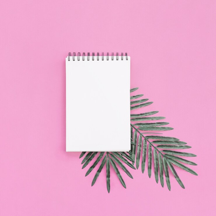 Foto gratuito cuaderno con hojas de palma sobre fondo rosa para maqueta