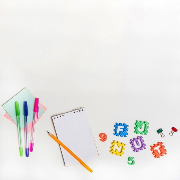 Cuaderno con lápiz cerca de plumas y letras