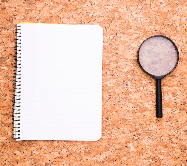 Cuaderno y lupa sobre escritorio.