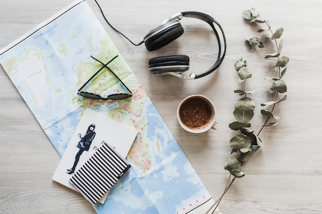 Cuaderno, mapa, café y auriculares en el escritorio de madera