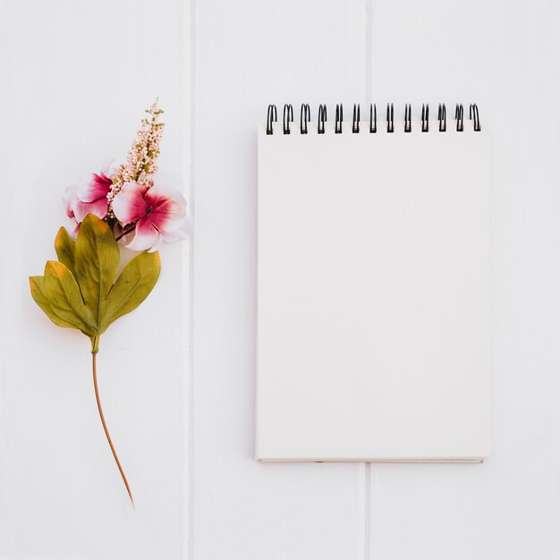 Cuaderno para maqueta con rosas sobre fondo blanco de madera