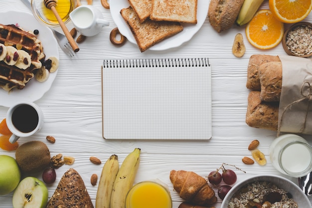 Cuaderno en medio de pasteles y frutas