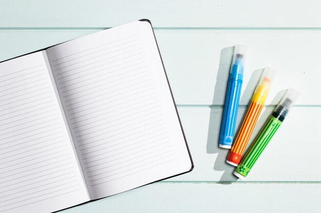 Cuaderno minimalista plano con marcadores