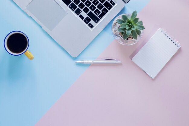 Cuaderno y planta cerca de teclado y café