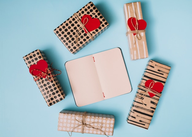 Cuaderno entre regalos en papel con corazones decorativos.