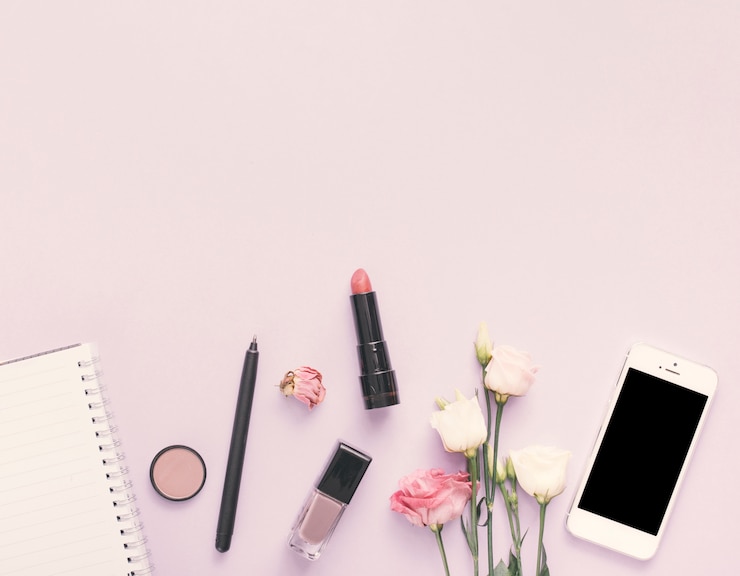 Foto gratuito cuaderno con smartphone, flor y cosmética en mesa de luz.