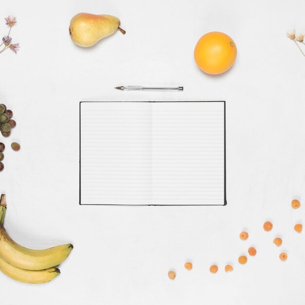 Cuaderno de una sola línea en blanco con lápiz y frutas saludables sobre fondo blanco