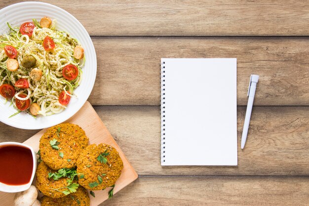 Cuaderno vacío junto a comida vegana