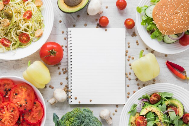 Cuaderno vacío rodeado de deliciosa comida vegana