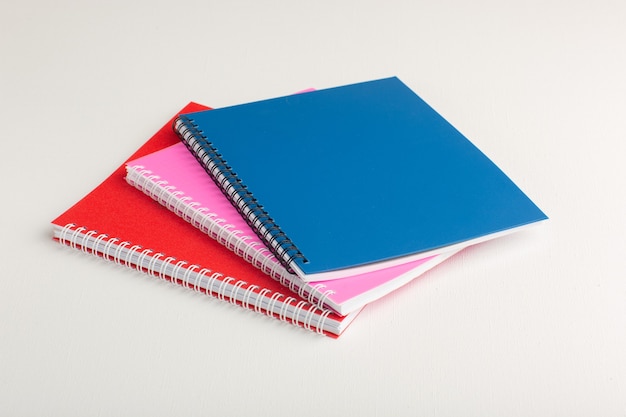 Cuadernos coloridos vista frontal sobre superficie blanca