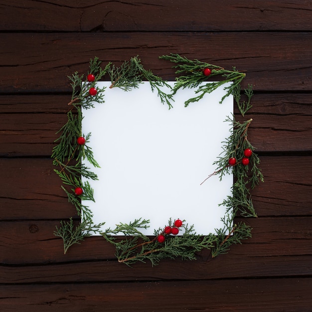 Cuadrado en blanco con pino de Navidad hojas alrededor sobre fondo de madera rústica