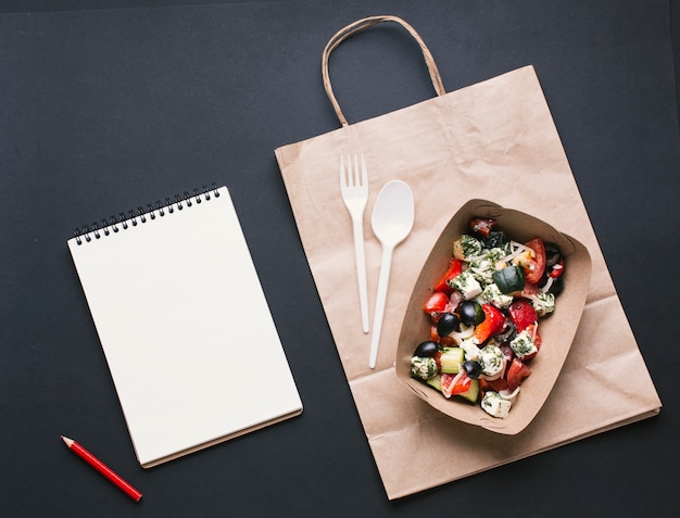 Foto gratuita cuadro de vista superior con ensalada en bolsa de papel