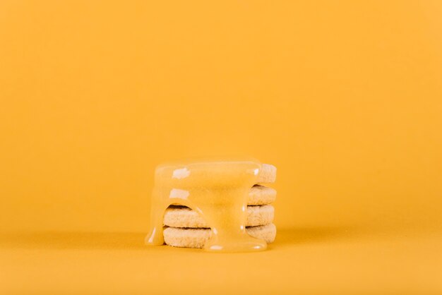 Cuajada de limón que gotea sobre la pila de galletas en el contexto amarillo