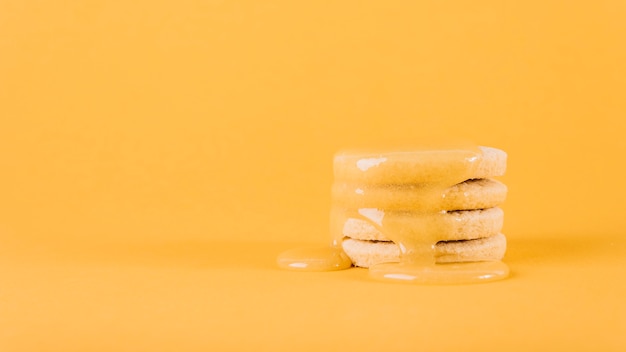 Cuajada de limón que gotea sobre la pila de galletas en fondo amarillo