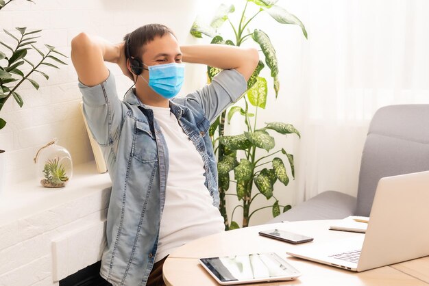 cuarentena debido a la pandemia del coronavirus. Quédate en casa. hombre de negocios que trabaja desde casa, use una máscara protectora. Trabaja desde casa con gel desinfectante. trabajo remoto, aprendizaje debido a la epidemia COVID-19.