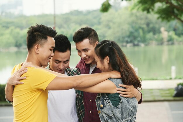 Cuatro amigos adolescentes abrazando al aire libre en el río