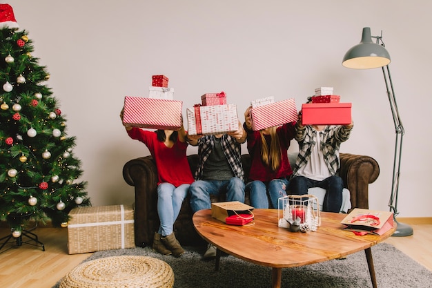 Foto gratuita cuatro amigos en sofá levantando regalos