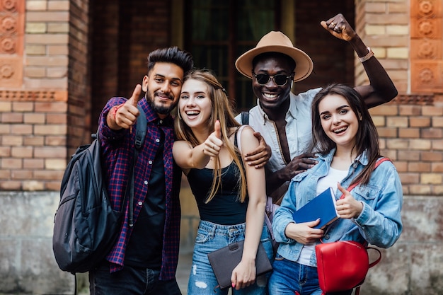 Cuatro estudiantes felices cerca de la universidad en el campus.