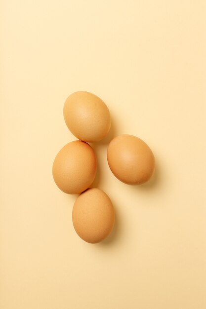 Cuatro huevos aislados en superficie amarilla