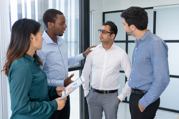 Cuatro jóvenes empresarios discutiendo estrategia de negociación antes de reunirse con los socios