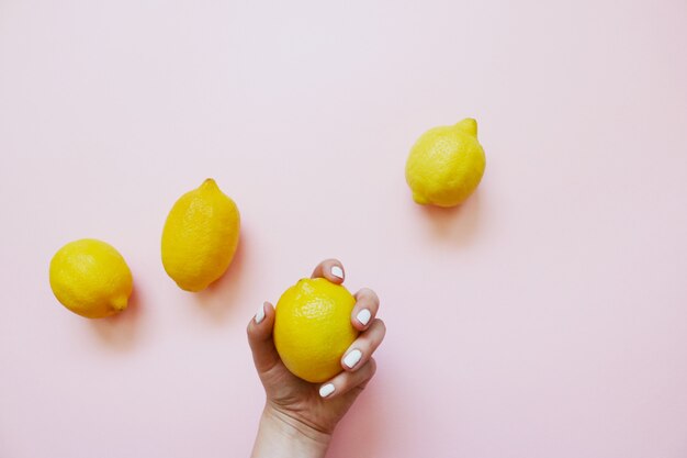 Cuatro limones amarillos sobre un fondo rosa