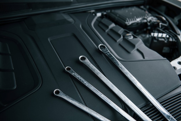 Cuatro llaves. Reparar herramientas apoyadas bajo el capó del automóvil. Color plata
