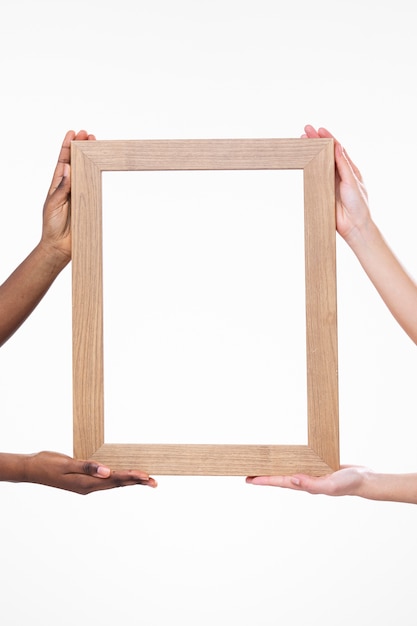 Cuatro manos sosteniendo marco de madera