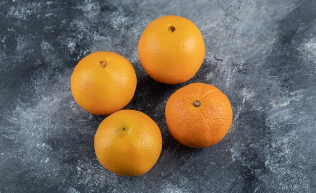 Cuatro naranjas sabrosas en la mesa de mármol.