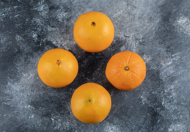 Cuatro naranjas sabrosas en la mesa de mármol.