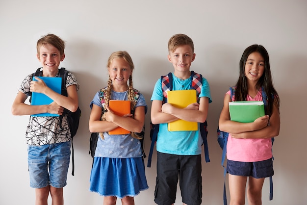 Cuatro niños sonrientes sosteniendo libros