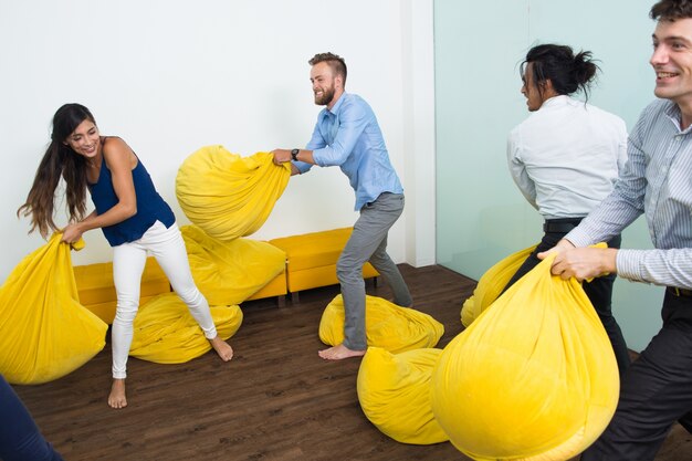 Cuatro personas juguetonas luchando con almohadas