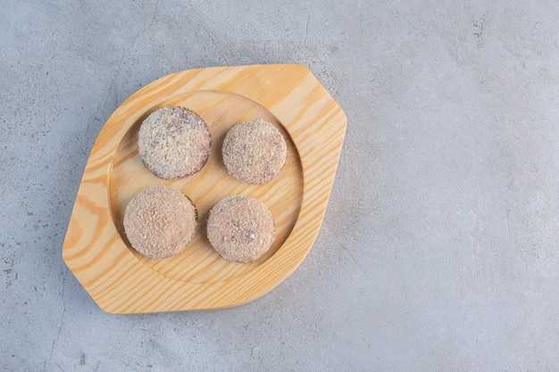 Cuatro sabrosas bolas de trufa colocadas en un plato de madera.