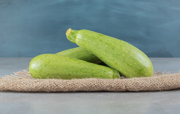 Cuatro verduras frescas de calabacín sobre una tela de saco. Foto de alta calidad