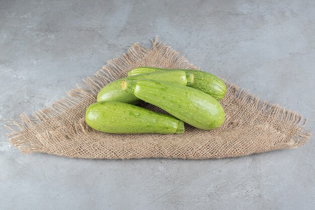 Cuatro verduras frescas de calabacín sobre una tela de saco. Foto de alta calidad