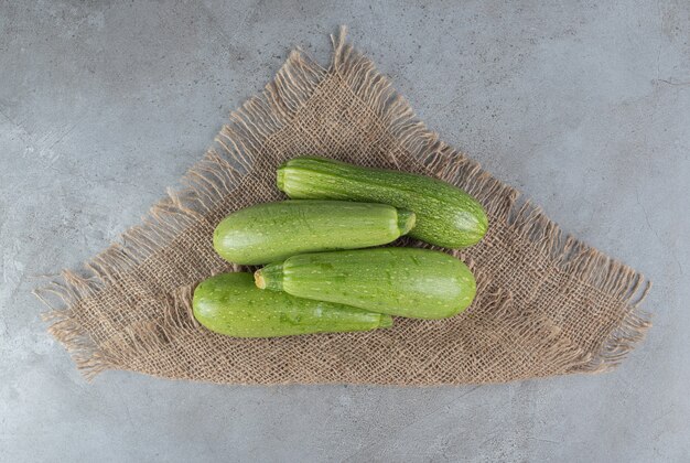 Foto gratuita cuatro verduras frescas de calabacín sobre una tela de saco. foto de alta calidad