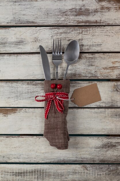 Cubiertos envueltos con motivo navideño en una mesa de madera