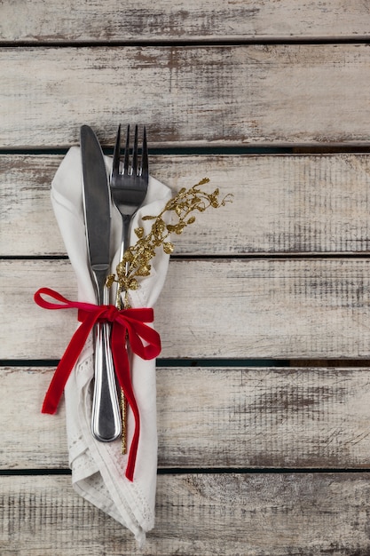 Cubiertos envueltos con motivo navideño en una mesa de madera