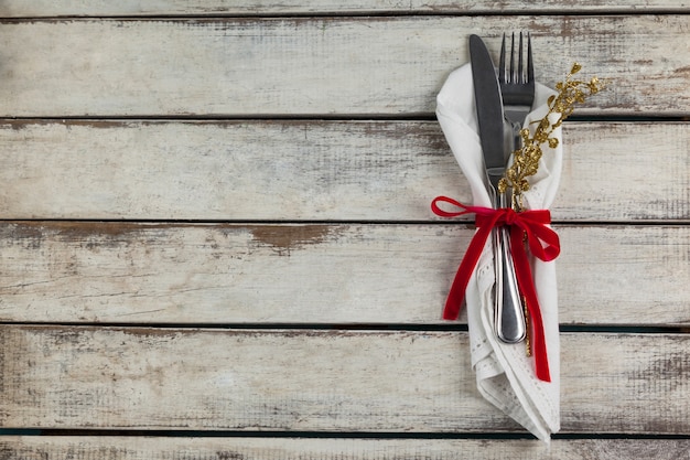 Cubiertos envueltos con motivo navideño en una mesa de madera