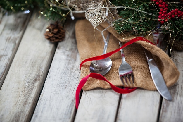 Cubiertos envueltos con motivo navideño en una mesa de madera