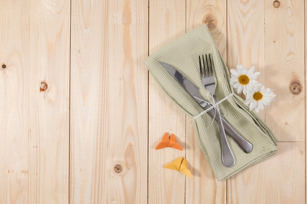 Cubiertos y flores sobre mesa de madera