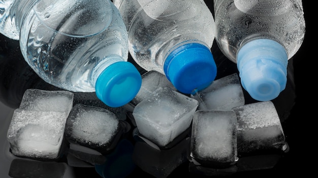 Cubitos de hielo y botellas de agua vista alta